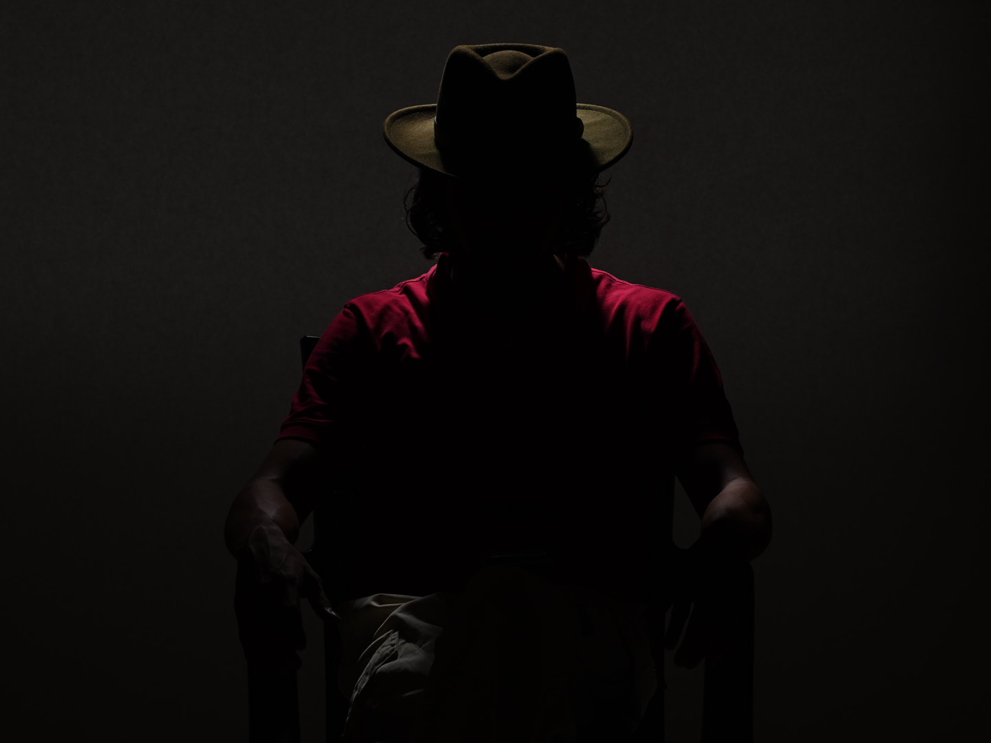 Dhaval Vanol seated in a studio, his signature hat silhouetted against the light