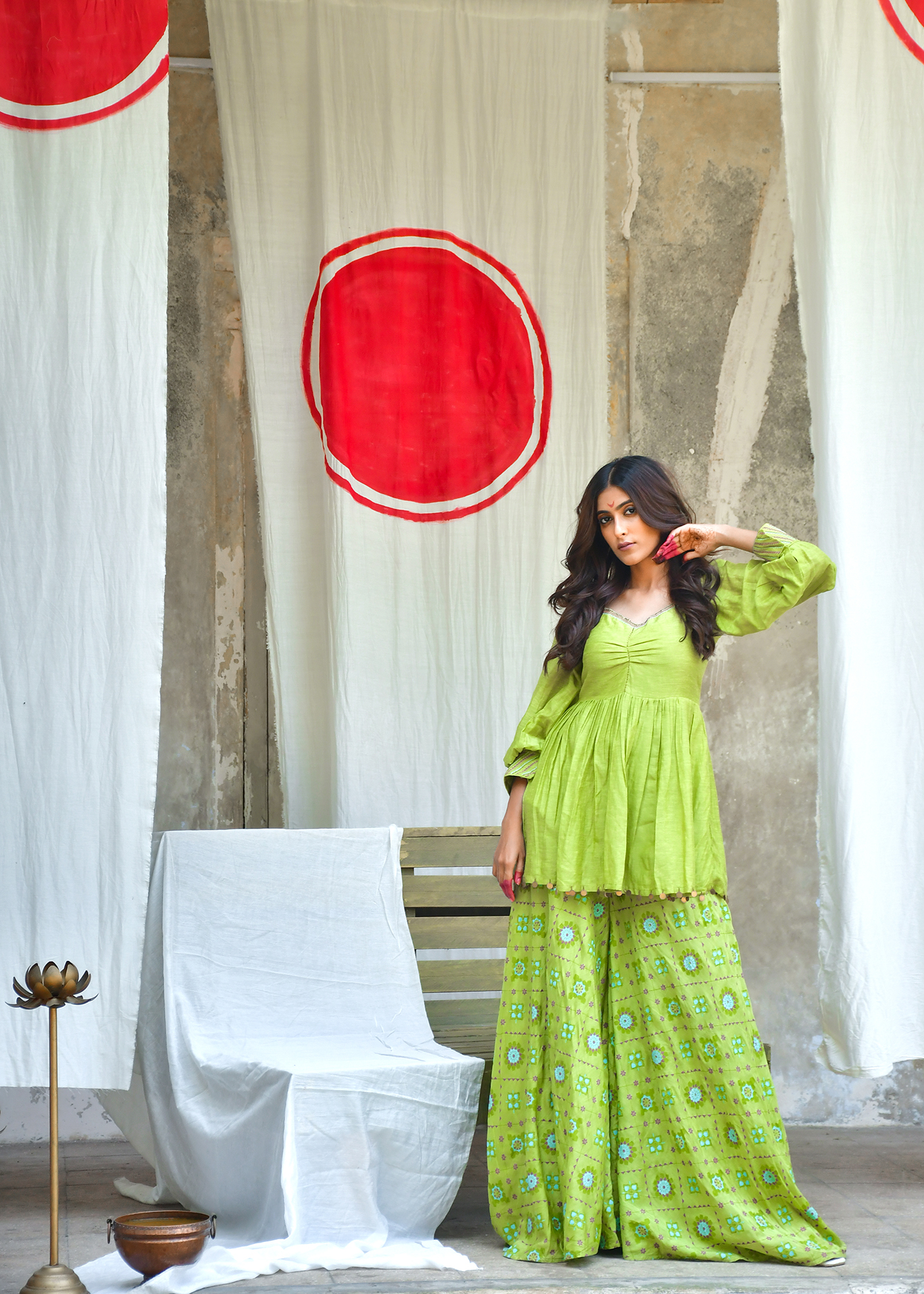 Model in a lime sharara against a sun motif backdrop